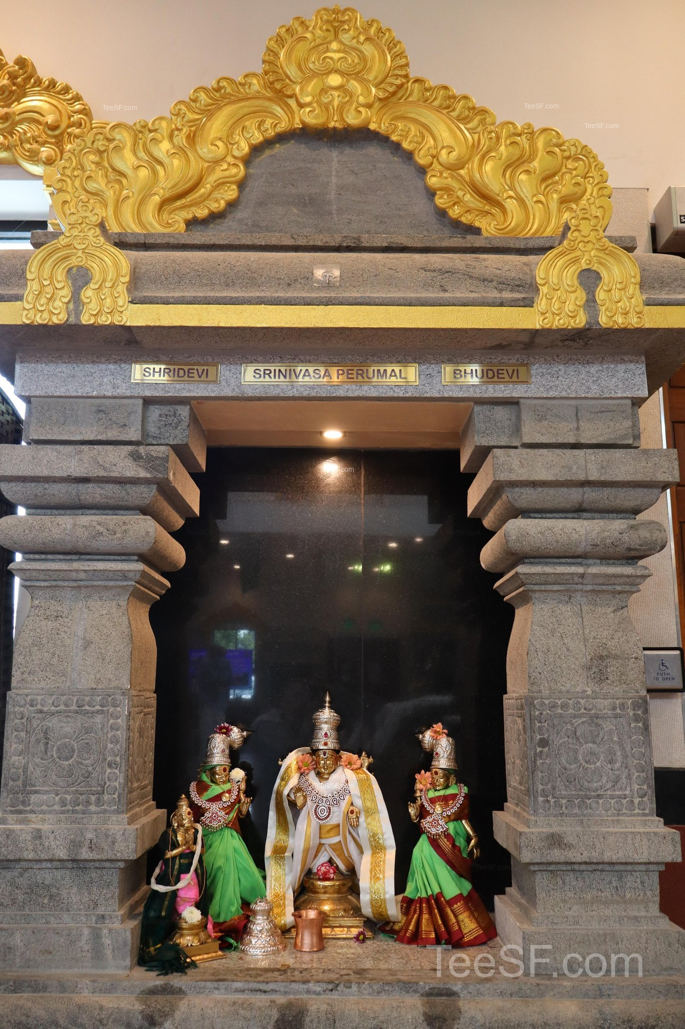 A small shrine entrance framed by gray stone and gold ornament.